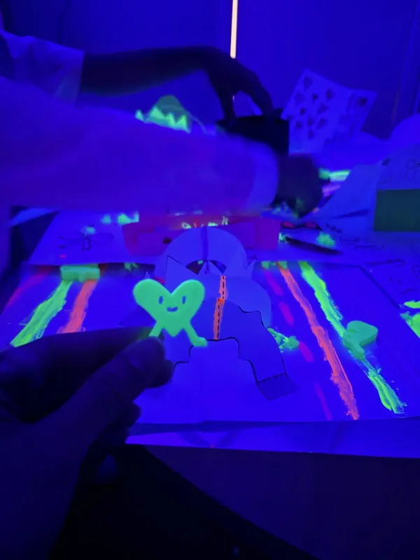 A glowing 3D-printed heart character standing on a paper planet