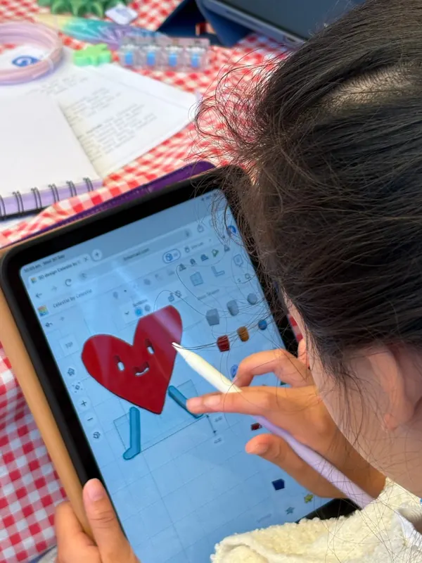 A child shapes a heart character in Tinkercad on an iPad