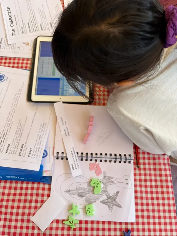 A child plans a planet in a sketchbook next to an iPad